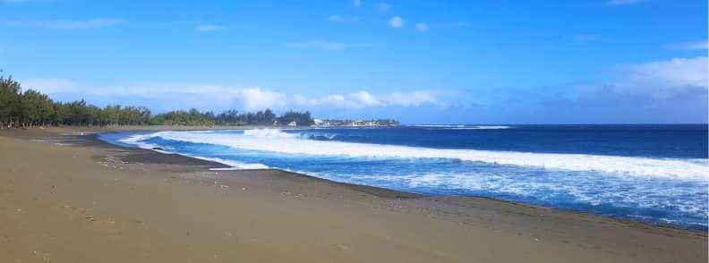 Wide black sand beach at Étang-Salé on Réunion Island with strong waves and open ocean
