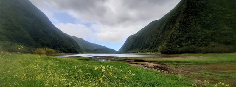Grand Etang crater lake on Reunion East Coast surrounded by rainforest mountains under cloudy sky