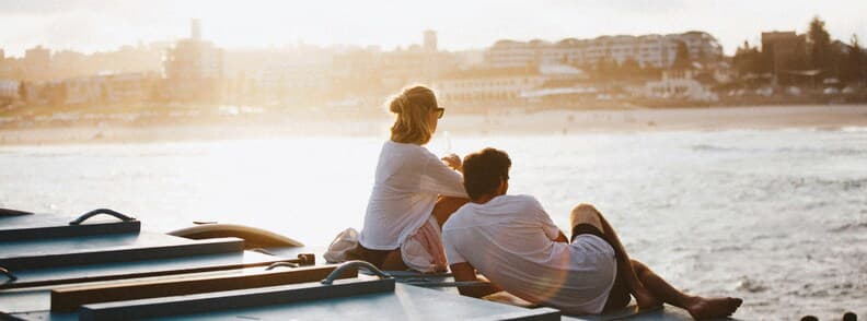 Partner Visa 820 and 801 Life in Australia Couple sitting by the ocean in Australia during sunset overlooking the coastline