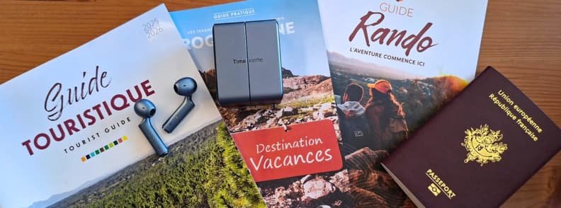 Timekettle W4 AI Interpreter Earbuds placed on travel guides and passport, showing translation earbuds as essential travel language gadgets for global travel.