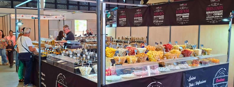 foire de brignoles local specialties hall des saveurs producers tasting provence Local specialty stand at the Hall des Saveurs at the Foire de Brignoles displaying dried fruits, spices, and regional products with visitors tasting.