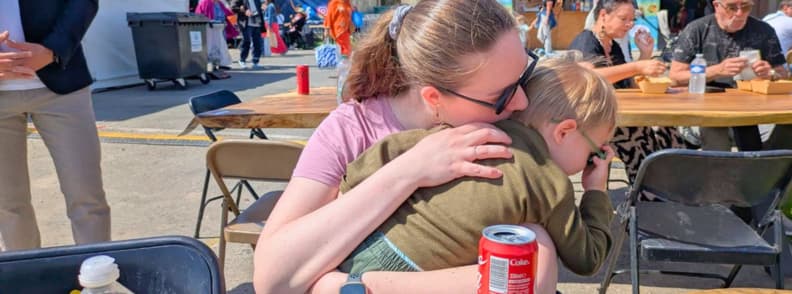 foire de brignoles with kids family guide travel bunny mirela letailleur Mirela Letailleur from The Travel Bunny holding her toddler son during a family visit to the Foire de Brignoles outdoor seating area.