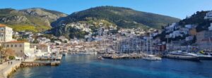 Saronic islands day trip from Athens cruise Aegina Poros Hydra harbor in Greece with sailboats, stone houses, and hills
