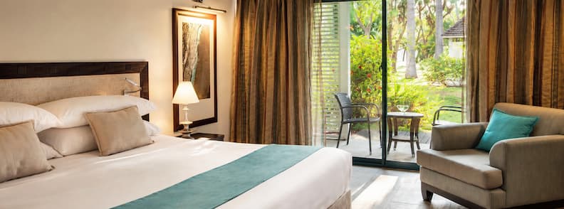 Where to Stay in Réunion accommodation guide. Bright hotel room in Saint-Gilles with garden access, king bed, and natural light through sliding doors