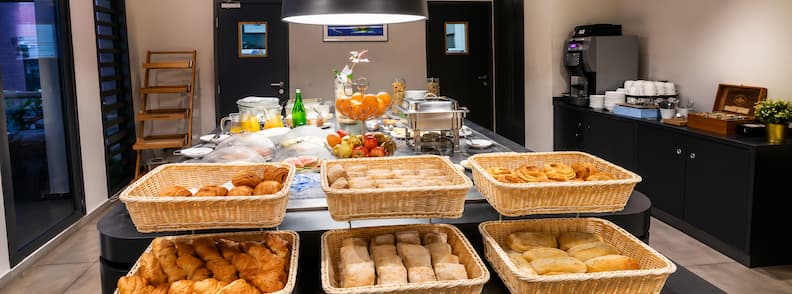 Breakfast buffet at Tulip Inn Sainte-Clotilde with fresh pastries, juices, and a modern dining setup in Saint-Denis.