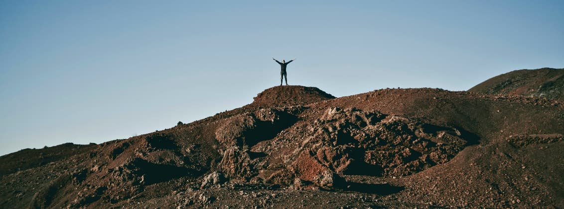 advanced hikes la reunion piton des neiges plaine des cafres Hiker standing on volcanic terrain in La Réunion during an advanced mountain hike across the island’s high-altitude landscapes.