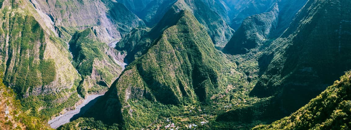 best time to visit la reunion for hiking cirques reunion island Mountain ridges and deep green cirques in La Réunion during hiking season, viewed from a high-altitude trail above the volcanic valleys.