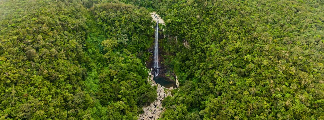 best time to visit la reunion month by month weather guide Aerial view of a waterfall surrounded by dense green forest in La Réunion during the island’s lush rainy season.
