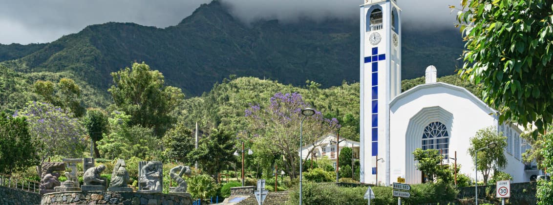 cirque de cilaos travel guide mountains waterfalls wine Church and mountain scenery in Cilaos, La Réunion, with lush green peaks, low clouds, and the village surrounded by volcanic landscapes.