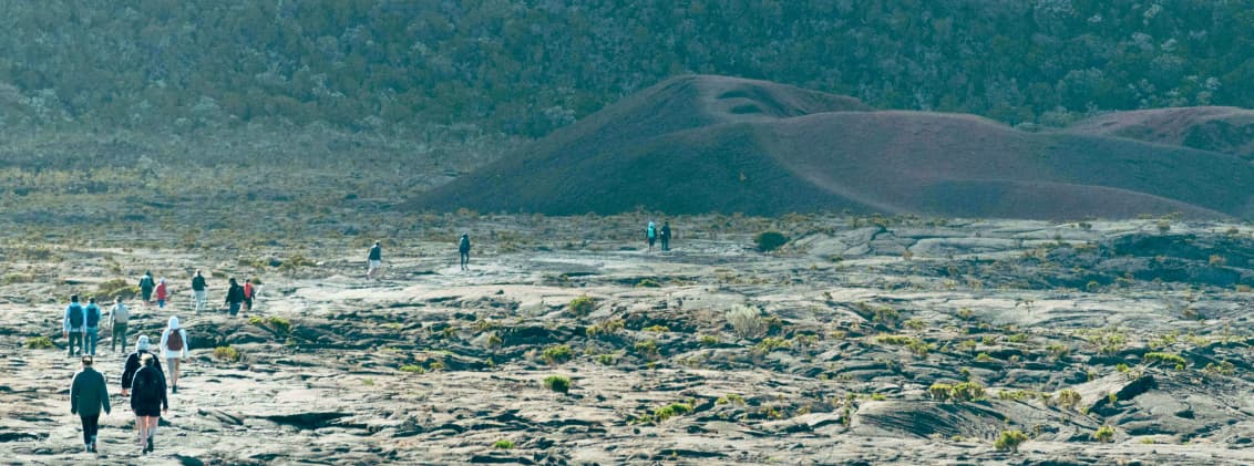 how many days in la reunion itinerary reunion island Travelers walking across volcanic terrain in La Réunion during a road trip itinerary through the island’s highland landscapes.