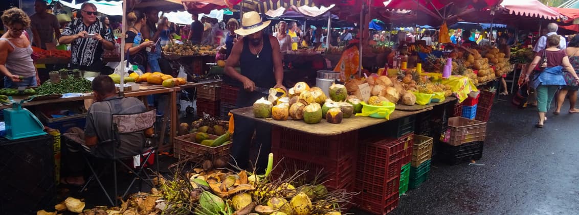 local markets la reunion creole food reunion island Busy local market in La Réunion with fresh tropical fruit, street food stalls, and vendors preparing coconuts for shoppers.