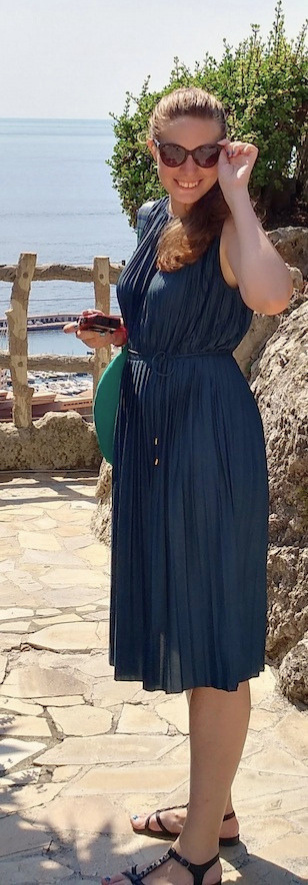 Mirela Letailleur standing above the Mediterranean coast in Monaco, surrounded by lush plants and stone terraces in the South of France.