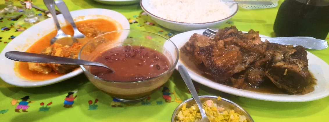 what to eat in la reunion creole food guide Traditional Creole meal in La Réunion with cari, rice, grains, achards, and local side dishes served on a restaurant table.