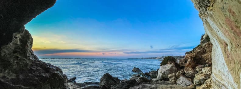 Anzio Beach and Rocky Coast on the Lazio Shore Rocky sea cave opening onto Anzio beach at sunset, with waves, boulders, and the Tyrrhenian Sea along the Lazio coast.