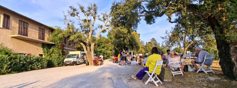 Guests dining outdoors beside food trucks and shaded tables at Château du Rouët before a Les Musicales dans les Vignes vineyard concert in Provence.