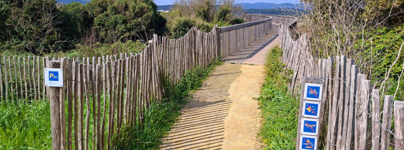 Wooden boardwalk entrance at the Étangs de Villepey with visitor regulation signs beside the protected wetland trail.