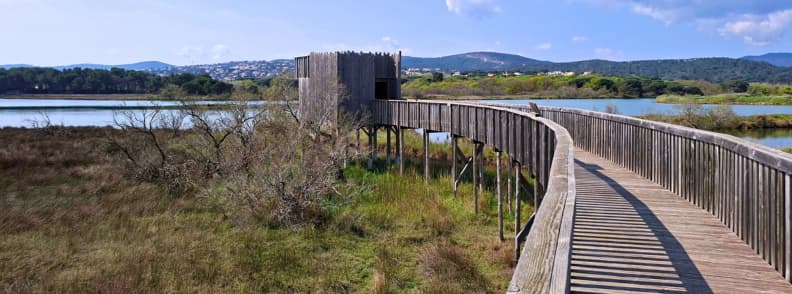 Wooden boardwalk leading to a birdwatching observatory over the Les Étangs de Villepey wetlands in Saint-Aygulf, Fréjus.