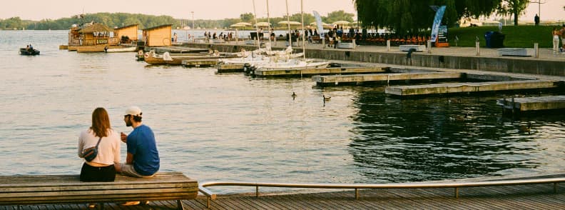 Toronto Waterfront Couples Weekend on Lake Ontario Couple sitting beside the water and docks during a romantic Toronto waterfront walk on Lake Ontario.