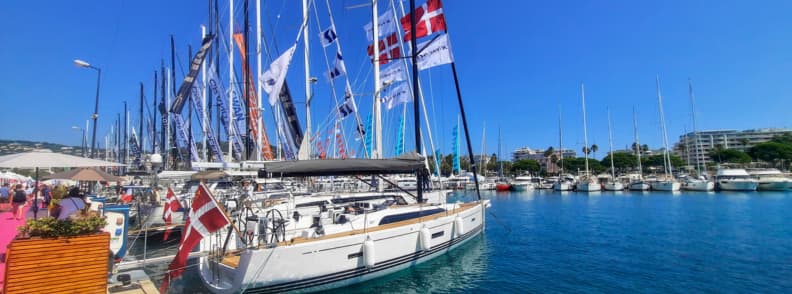 Cannes Yachting Festival and French Riviera Autumn Sailing Sailing yachts displayed in Cannes during the Cannes Yachting Festival, with masts, flags, marina berths, and blue Mediterranean water.