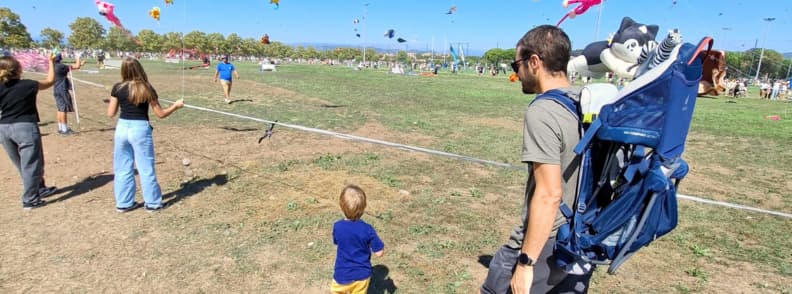 Frejus Air Festival Family Visit Giant Kites My husband and 2-year-old son walking beside the giant kite fields at the Fréjus International Air Festival 2026, with colorful XXL kites flying over Base Nature François Léotard.