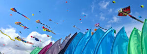 Colorful stunt kites and wind installations filling the blue sky at the Fréjus International Air Festival at Base Nature François Léotard on the French Riviera.