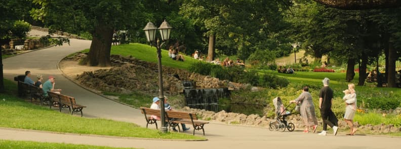 Planty Park Krakow Old Town Walking Route People walking and resting beside shaded paths, benches, and greenery in Planty Park around Kraków Old Town.