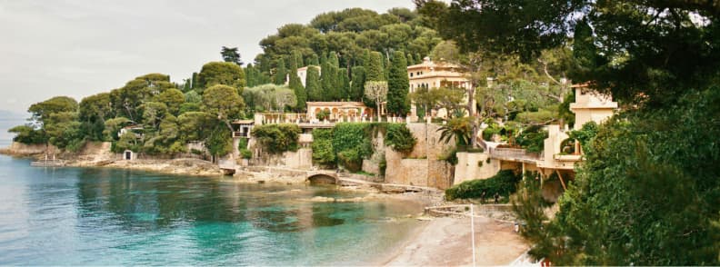 Saint Jean Cap Ferrat Coastal Paths in Autumn Coastal path in Saint-Jean-Cap-Ferrat in autumn, with turquoise Mediterranean water, wooded villas, and a quiet beach on the Côte d’Azur.