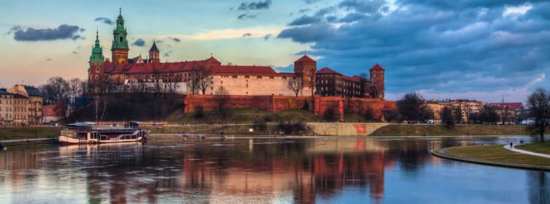 Wawel Royal Castle on Wawel Hill reflected in the Vistula River at sunset in Kraków, Poland.
