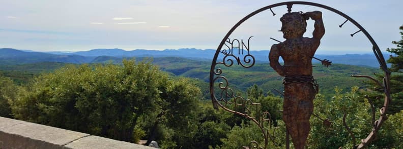 Best Time to Visit Mons Var Panorama and Saint Sebastian Wrought-iron Saint Sebastian figure at the Mons Var viewpoint, with forested Pays de Fayence hills and distant ridges under a clear sky.