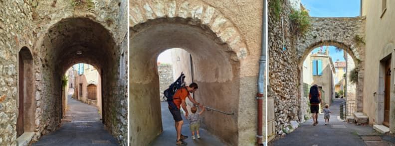 Family Walk Through Stone Arches in Mons Var Father and toddler walking through narrow stone archways in Mons Var, with old village houses and paved lanes beyond.